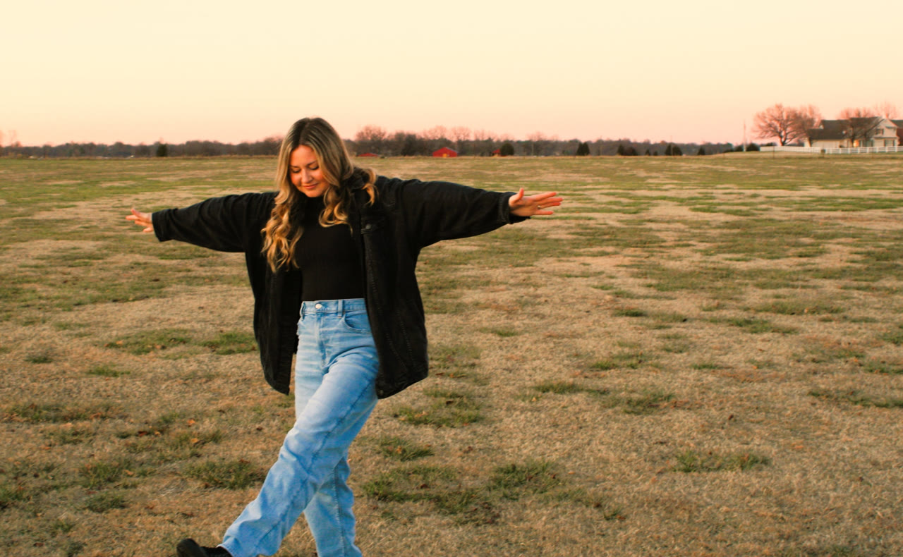 Leah Smith, walking through an open field at sunset